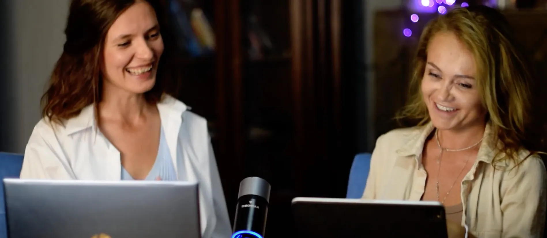 Two finance people laughing over laptops during a late working session